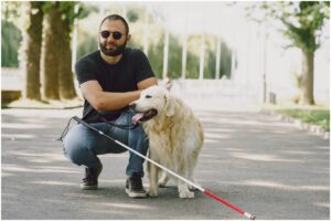 Persoană cu deficiențe de vedere și un câine ghid