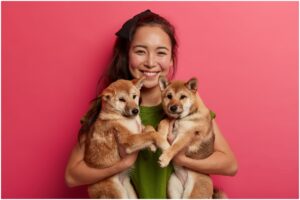 femeie cu doi pui de câine în brațe